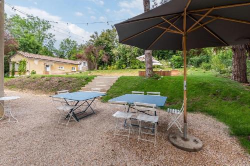 - une table de pique-nique et des chaises avec un parasol dans l'établissement La clarté - wonderful refurbish home with garden and pool, à Champagne-au-Mont-dʼOr