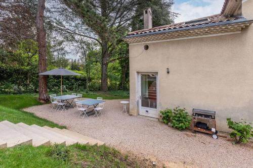 un patio avec une table, des chaises et un parasol dans l'établissement La clarté - wonderful refurbish home with garden and pool, à Champagne-au-Mont-dʼOr