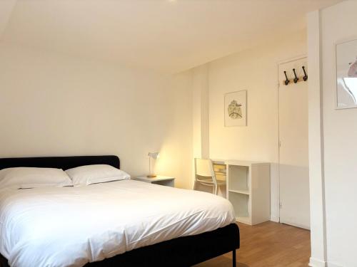a bedroom with a white bed and a table and chairs at Duplex rénové pour 6 voyageurs - Roubaix in Roubaix