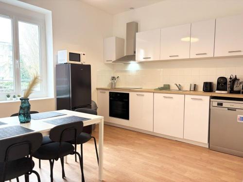 une cuisine avec des armoires blanches et une table avec des chaises dans l'établissement Duplex rénové pour 6 voyageurs - Roubaix, à Roubaix