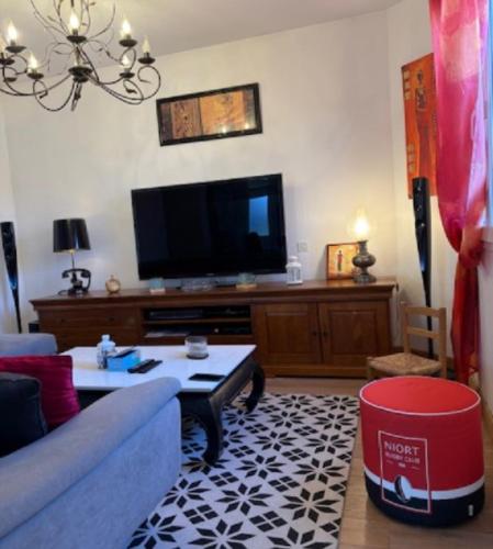un salon avec un canapé bleu et une télévision dans l'établissement Bienvenue à la maison !, à Vouillé