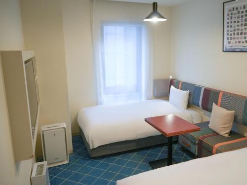 a hotel room with a bed and a table at Rembrandt Style Yokohama Sakuragicho in Yokohama