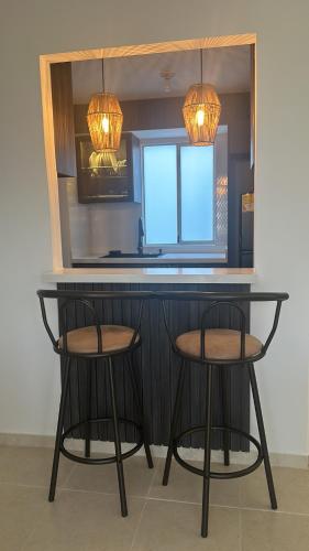 a kitchen with two stools and a counter with two lights at Apartamento Frente a la Clinica Valle del Lili in Cali