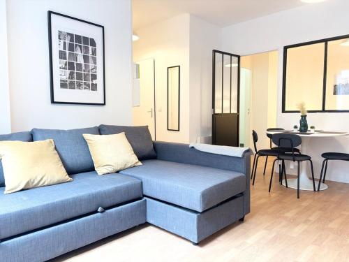 un salon avec un canapé bleu et une table dans l'établissement Grand appartement avec terrasse - 4 voyageurs, à Roubaix