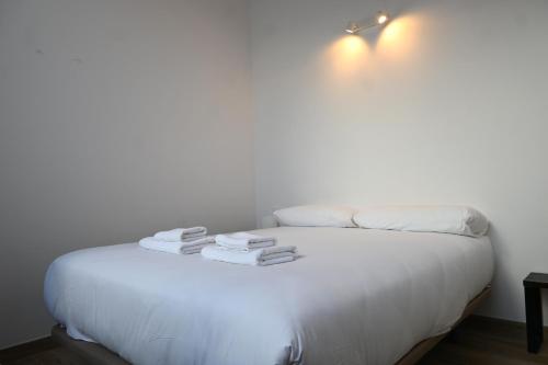 a white bed with towels on top of it at Homenfun Dalt Badalona in Badalona