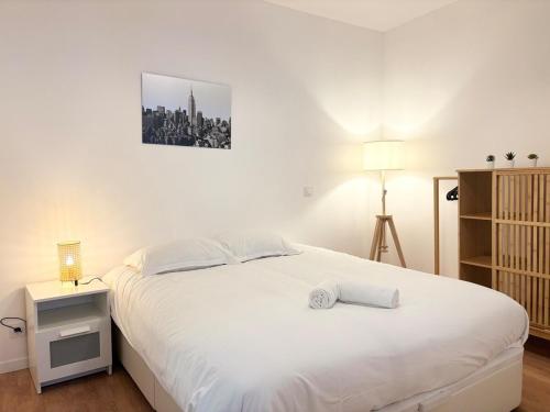 - une chambre avec un lit blanc et une table de nuit dans l'établissement Grand appartement avec terrasse - 4 voyageurs, à Roubaix