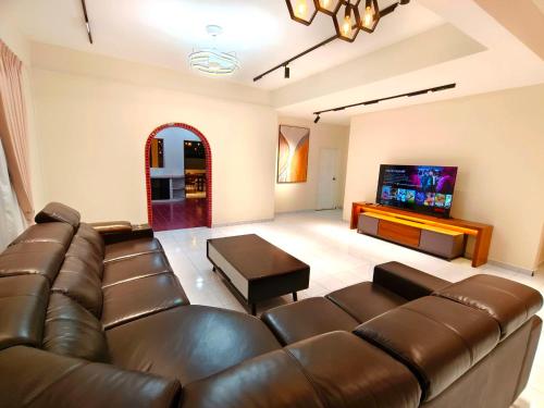 a living room with a leather couch and a flat screen tv at SunsetChalet 25pax Pool Snooker Bathtub Playground in Kluang