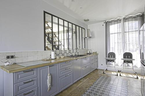 une cuisine avec un évier et un comptoir avec deux tabourets dans l'établissement Villa d'exception au coeur de Deauville, Jardin & Cinéma privé, à Deauville