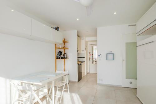 une cuisine blanche avec une table et des chaises blanches dans l'établissement Studio Marina Baie Des Anges, à Villeneuve-Loubet