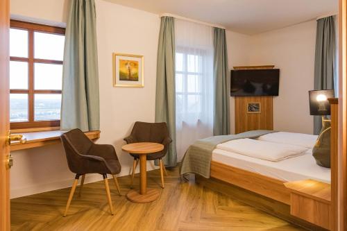 a hotel room with a bed and a table and chairs at Hotel Neckarblick in Bad Wimpfen
