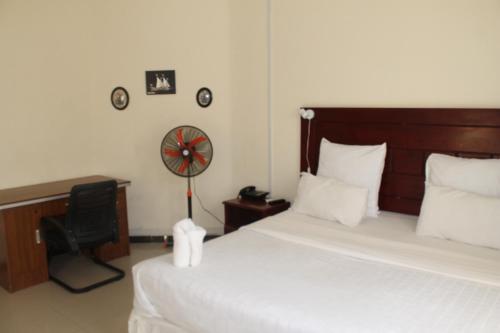 a bedroom with a bed and a desk and a fan at Honeybed Lodge in Lusaka