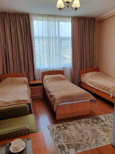 a bedroom with two beds and a window at Aquamarine Inn in Cholpon-Ata