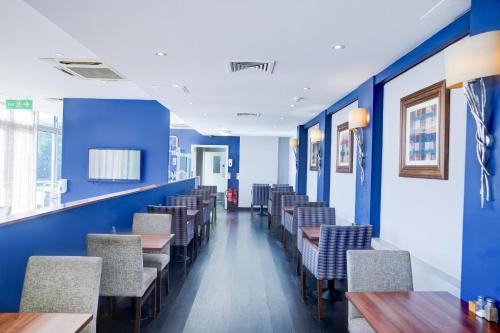 a dining room with blue walls and tables and chairs at Dancenter near Stoke On Trent former Holiday Inn in Crewe