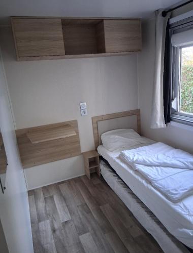 une petite chambre avec un lit et une fenêtre dans l'établissement Charmant mobil-home N°698 3ch tout confort au calme, à Gastes