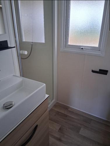 une salle de bain avec un lavabo et une fenêtre dans l'établissement Charmant mobil-home N°698 3ch tout confort au calme, à Gastes