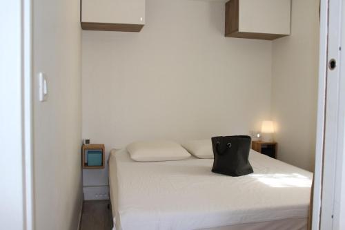 - une chambre dotée d'un lit blanc avec un sac noir dans l'établissement Maison 2 pièces mezzanine - Gruissan GN020-071, à Gruissan