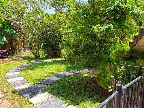 a garden with a stone walkway next to a fence at LaRoy FutureStay - Smart Hotel Mirissa in Mirissa