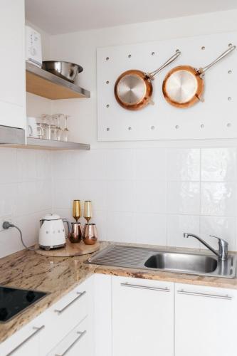a kitchen with white cabinets and a sink at Portsea 74 - Live a little in Port Douglas