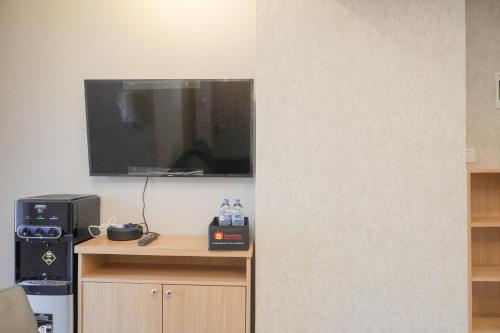 a room with a desk with a tv on the wall at Homey 2BR at Tokyo Riverside PIK 2 Apartment By Travelio in Rawalembang