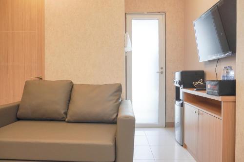 a living room with a couch and a television at Homey 2BR at Tokyo Riverside PIK 2 Apartment By Travelio in Rawalembang