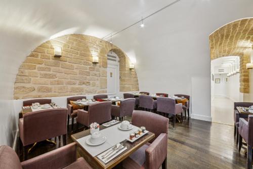 une salle à manger avec des tables et des chaises et un mur en briques dans l'établissement Victoires Opera, à Paris