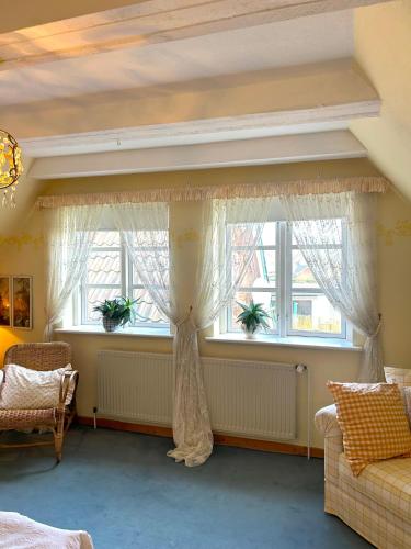 a living room with two windows with curtains at Landhaus Hüttblek in Hüttblek