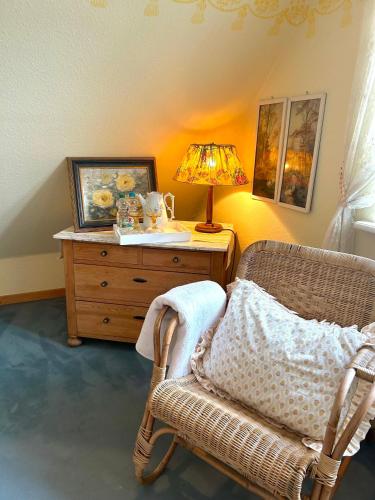 a bedroom with a chair and a table with a lamp at Landhaus Hüttblek in Hüttblek