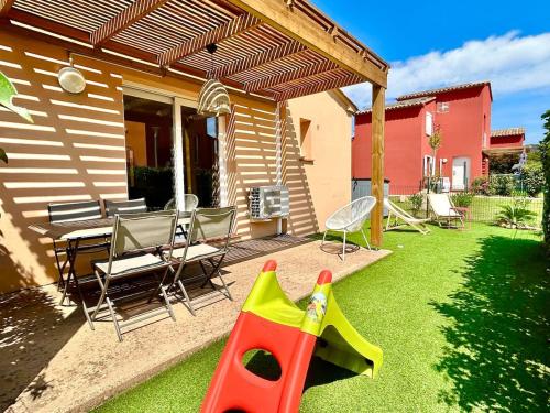 une cour avec une aire de jeux avec un jouet en plastique sur l'herbe dans l'établissement Mini villa T3 de 48m2, à Lecci