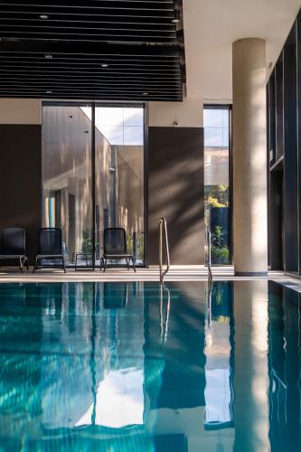 a swimming pool with two chairs in a building at Shellter Hotel Resort & Spa in Rogowo
