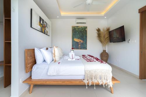 a bedroom with a white bed with a table at Salthouse Villa Uluwatu in Uluwatu