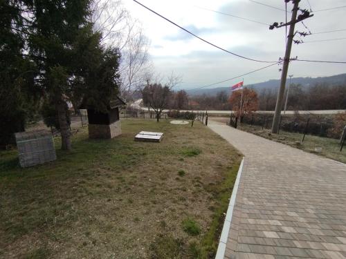 a brick walkway with a bench in a park at Kosmaj Apartmani Košutica - Marija i Ksenija in Koraćica