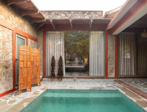 a swimming pool in a room with a large window at Neem Sarai Sariska in Tehla