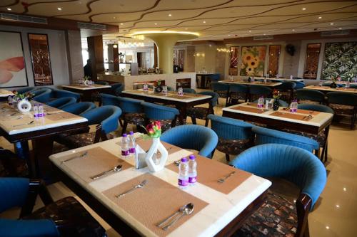 a dining room with tables and blue chairs at Hotel Hello Jeypore in Jaypur