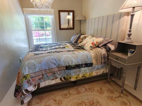 a bedroom with a bed and a window at Charming Rose Cottage in Greyton