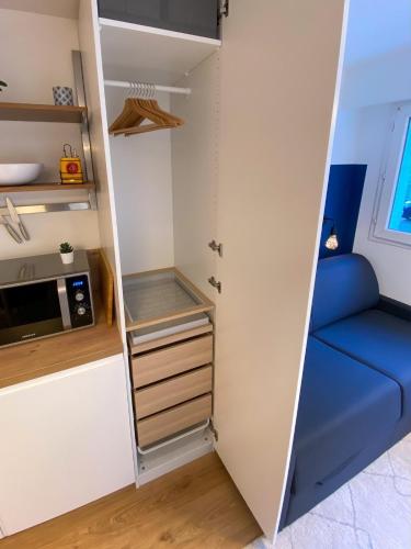 Il comprend une petite cuisine avec un placard et un canapé bleu. dans l'établissement Rieux Studio -2p refurbished!, à Nantes