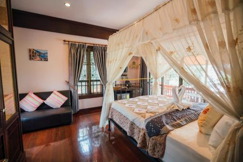 Un dormitorio con una cama con dosel y un sofá. en Ban Thong U, The Landmark, en Chiang Mai