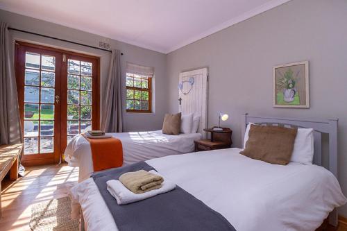 a bedroom with two beds and a balcony at Beloftebos Farm Cottages in Papiesvlei
