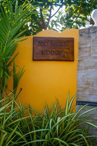 a sign that reads mind aidle lodge on a yellow wall at Nid'Aigle Lodge in Anse Possession