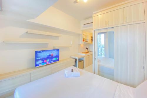 RawalembangCozy and Well Furnished Studio Tokyo Riverside PIK 2 Apartment By Travelio的一间带床和电视的白色卧室