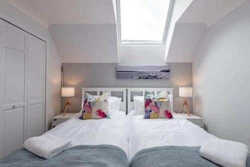 a bedroom with a white bed with pillows and a window at Abbey Villa - No 5 in St. Andrews