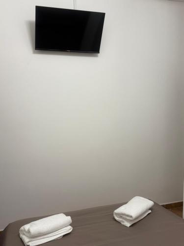 two towels on a table with a tv on a wall at Little House in Fiumicino