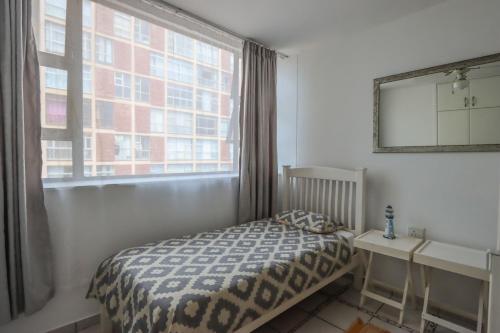 a bedroom with a bed and a large window at 504 Amazibu Holiday Flat- Paradise on the Beach in Amanzimtoti