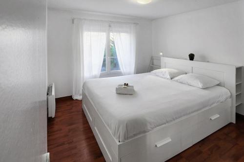 une chambre blanche avec un lit blanc avec un sac à main dessus dans l'établissement Cosy Charpennes, à Villeurbanne