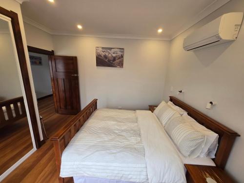 a bedroom with a bed with white sheets and pillows at Villa 191 in Masterton