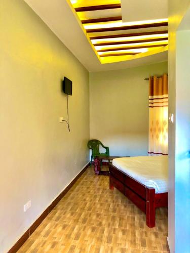 a room with a bed and a tv on the ceiling at JOMRY COTTAGEs in Nsangi