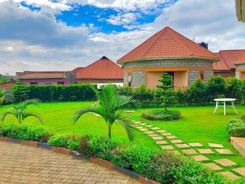 a house with a green yard with a table in it at JOMRY COTTAGEs in Nsangi