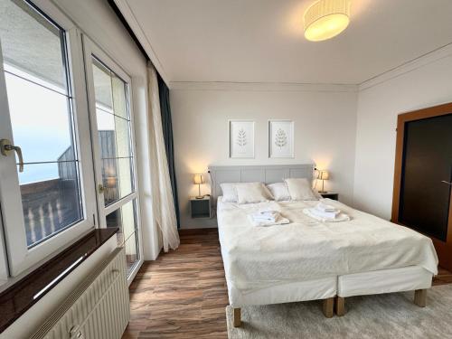 a bedroom with a white bed and a large window at Hochkogelhaus - flying oasis, Hohe Wand in Maiersdorf