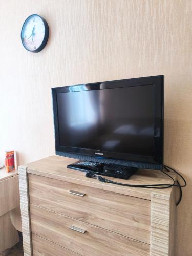 a television on a dresser with a clock on the wall at Гостиничный комплекс Алтай in Lenīnogorsk