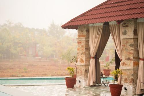 a pavilion with plants in pots next to a pool at Neem Sarai Sariska in Tehla