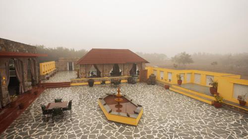 a building with a gazebo and a table and chairs at Neem Sarai Sariska in Tehla